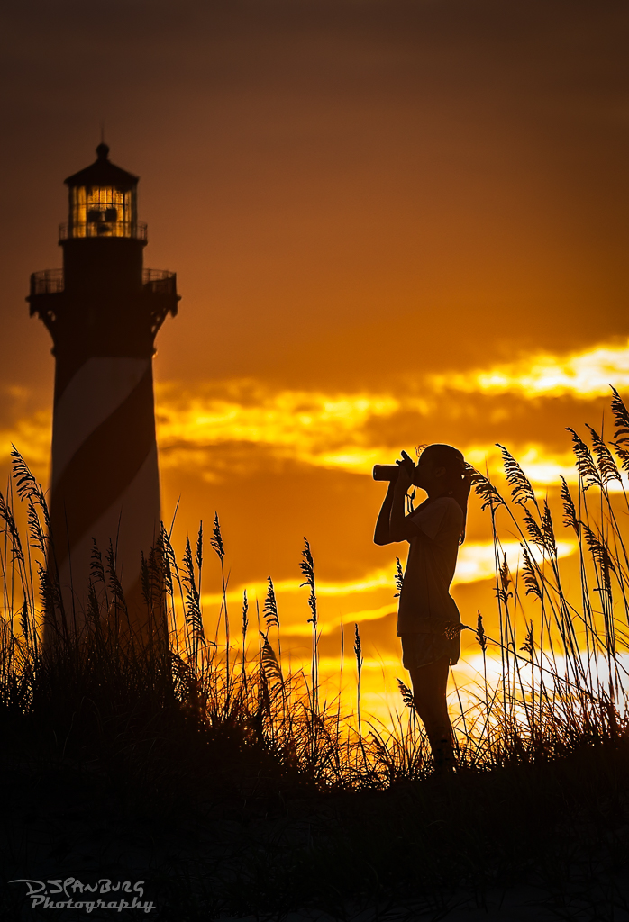 Photo of a girl silhouette taking a photograph of the Cap Hatteras lighthouse
